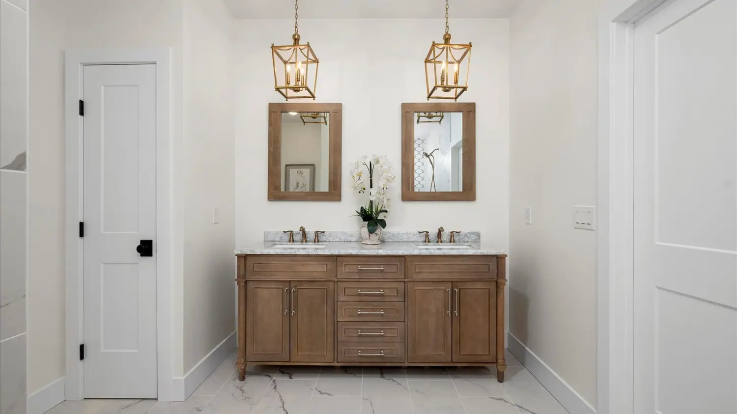 Primary en-suite bathroom with a wood double vanity and marble floor