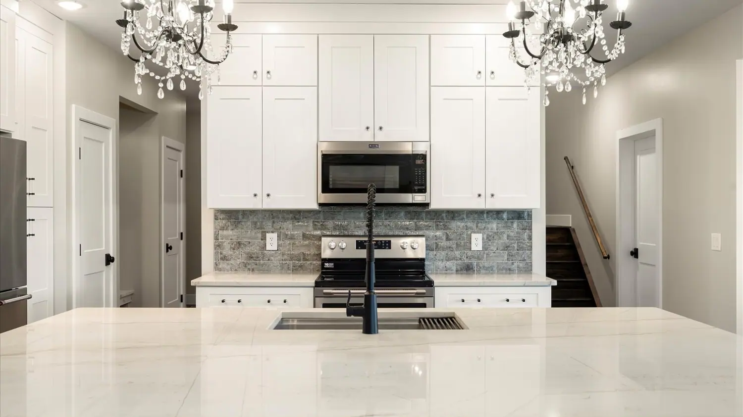 Kitchen with a glass backsplash, central island and pendant lighting