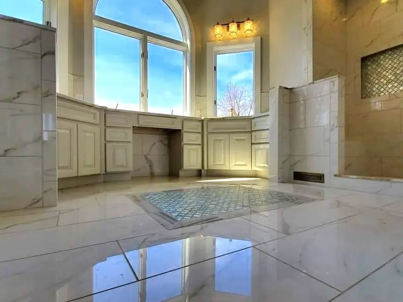 Primary bathroom with light cabinetry and a polished marble floor