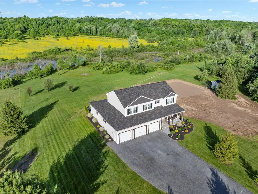 A finished home seen from above, with its drive and surrounding land